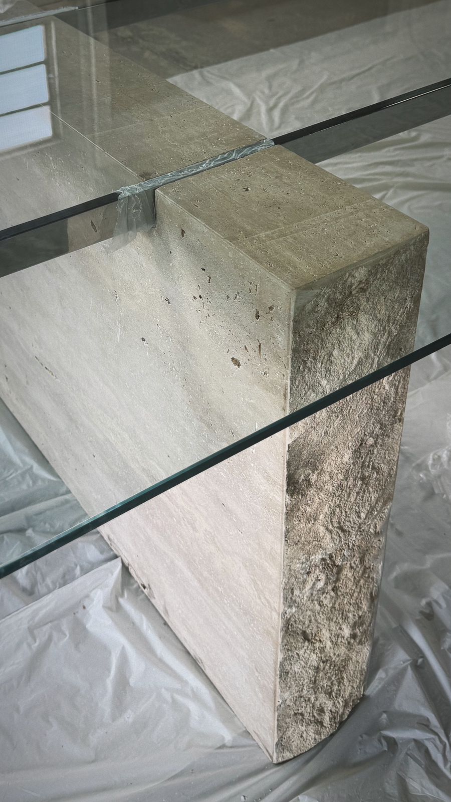Mesa com tampo em vidro incolor de 10mm temperado com haste inox e os pés em travertino romano